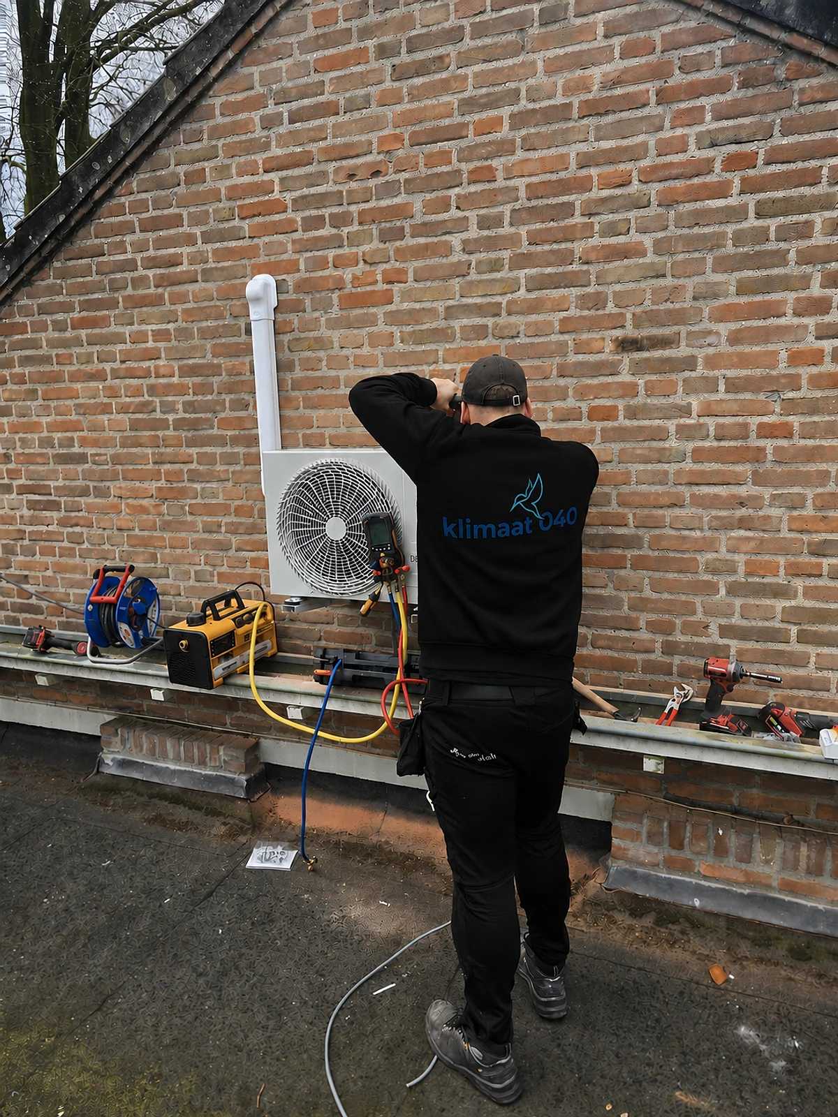 Klimaat 040 monteur installeert een airco-buitenunit
